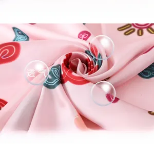 Detail of silk scarf showing smooth texture and colorful abstract pattern on soft pink fabric