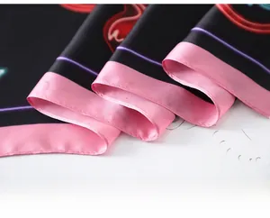 Detail of meticulous flat-seam stitching on a black silk scarf with pink contrast piping