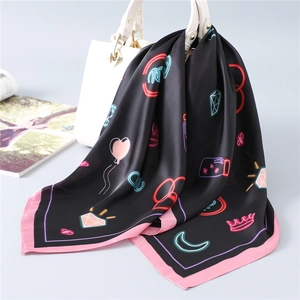 Detail of neon graffiti silk scarf tied on a white bag, highlighting glossy satin texture