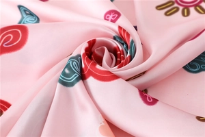 Macro shot of pink silk scarf showing smooth satin texture and colorful tribal patterns