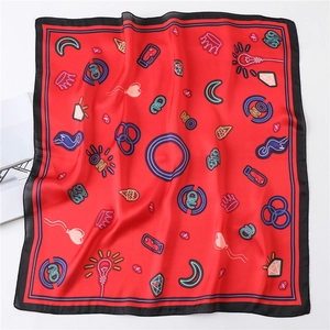 Close-up of red silk scarf showing playful graffiti crown patterns and soft fabric texture