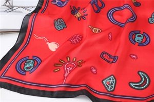 Detail view of red silk scarf with cartoon crown prints and black stitched edges