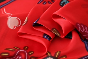 Macro view of smooth red silk scarf with cartoon heart and crown artistic patterns
