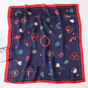 Detail of navy blue silk scarf with red border and neon crown patterns on white background