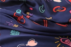 Close-up of silk scarf fabric showing neon heart prints and a smooth satin texture