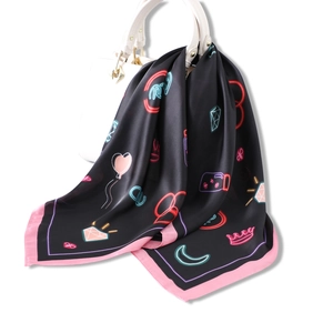 Black silk square scarf with neon heart and crown patterns tied to a white handbag