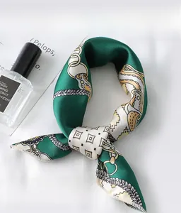 Close-up of green chain print silk scarf with fine rolled edges on white fabric