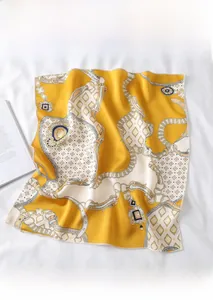 Detail of yellow silk-like square scarf with retro chain print on a white fabric