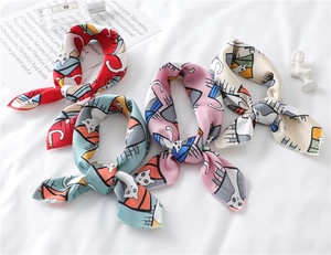 Detail of silk narrow scarves with cartoon cat prints on white textured fabric