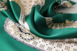 Detailed view of silk-like emerald scarf with golden chain and baroque geometric pattern