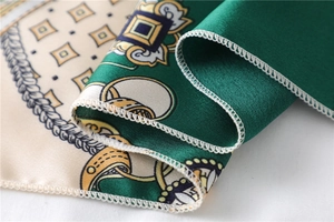 Close-up of luxury satin scarf with emerald green baroque chain print and silk texture