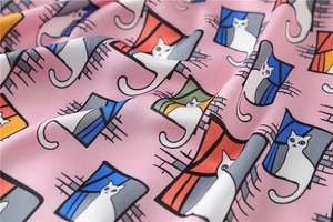 Close-up of pink satin scarf fabric featuring cute white cat and window pattern prints
