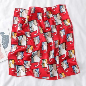 Detail of red satin scarf with cute white cat print on white wrinkled fabric