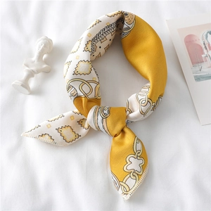 Detail of elegant chain pattern silk scarf in ginger yellow and ivory white on white fabric