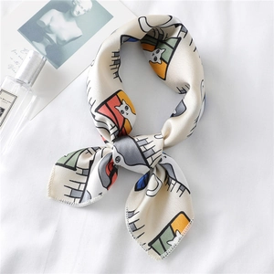 Elegant cream silk scarf with colorful cartoon cat patterns laid on a white fabric