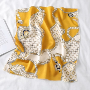 Detail of silk-like scarf with chain and leather belt pattern on white tablecloth