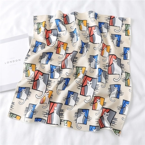 Detailed close-up of a silk scarf with cartoon white cat patterns and fine stitched edges