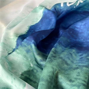 Close-up of silk satin scarf showing abstract watercolor dye in navy and teal