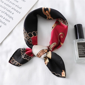 Close-up of a satin silk scarf with golden chain pattern and lifestyle props
