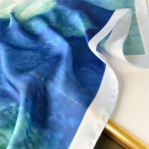 Detailed texture of blue watercolor print silk scarf with glossy finish and white hem edge