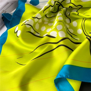 Detailed texture of vibrant neon yellow silk scarf with black abstract print and blue border
