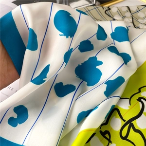 Detailed view of silk-like scarf with royal blue dots and neon yellow artistic prints