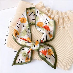 Detail of floral printed silk scarf tied in a bow on soft textured fabric background