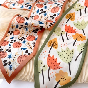 Detail of silk-like fashion scarves with pumpkin and abstract leaf floral patterns