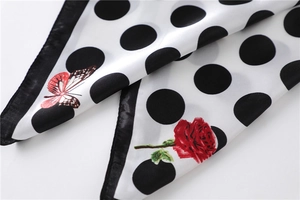 Detail eines Seidenschals mit großen schwarzen Punkten, roten Rosen und Schmetterlingen