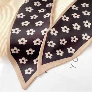 Detail of floral print silk scarf featuring white daisies and gold piping edges