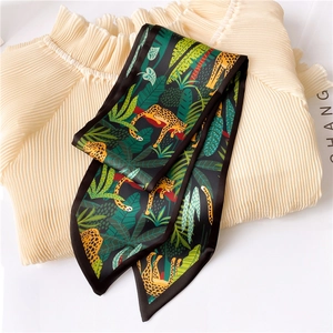 Detail of dark green silk scarf with leopard and tropical leaf print on beige fabric