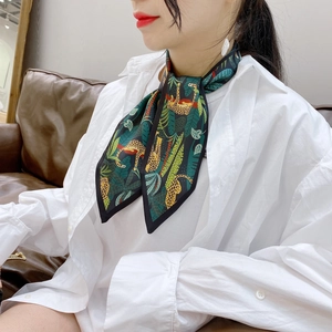 Detail of a leopard and tropical leaf print silk scarf tied on a white shirt collar