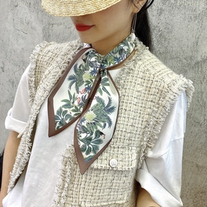 Close-up of tropical palm and bird print skinny silk scarf worn as a fashion necktie