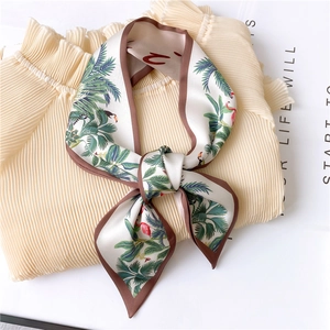 Detail of tropical print silk scarf featuring flamingos and palm leaves with brown edging