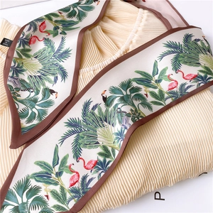 Detail of printed silk scarf with tropical flamingos and palm leaves on pleated fabric