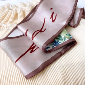 Macro detail of silk-like scarf featuring pink floral print and brown contrast edges