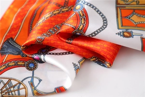 Detailed macro of silk satin scarf featuring luxury chain and carriage print patterns