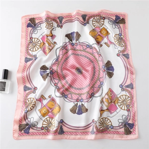 Close-up of pink silk scarf with vintage carriage, chain, and pearl pattern on white table