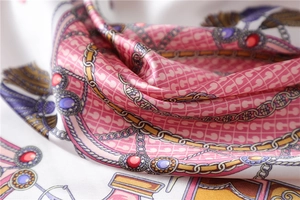 Detail of silk-like satin scarf featuring gold chains and gemstone print patterns