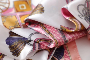 Close-up of silk scarf showing luxury chain patterns and soft satin fabric texture