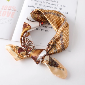 Detail of champagne gold satin scarf with carriage and chain prints on a magazine
