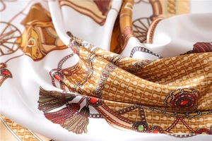 Close-up of silk satin square scarf with classic horse carriage and golden chain print