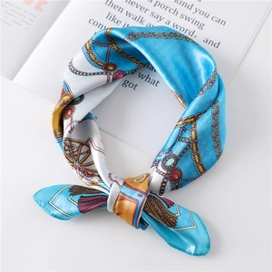 Detail of luxury silk scarf with chain pattern and carriage design on magazine