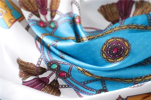 Detailed shot of luxurious blue silk square scarf with golden chains and tassel patterns