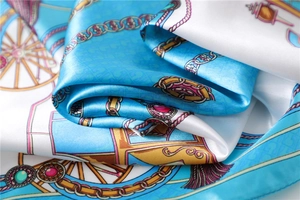 Detailed close-up of blue baroque satin scarf with vintage carriage and gold chain prints