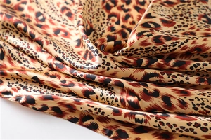 Macro detail of silky satin leopard print fabric with glossy texture and smooth drapes