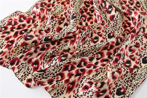 Detailed view of leopard print satin scarf with smooth silk-like texture and red-beige patterns