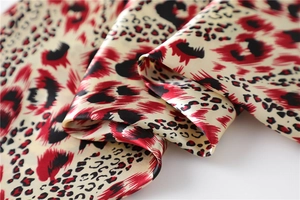 Macro detail of leopard print satin scarf showing smooth silk texture and red pattern