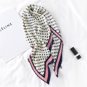Détail d'un foulard en soie plissé beige à pois avec des finitions élégantes