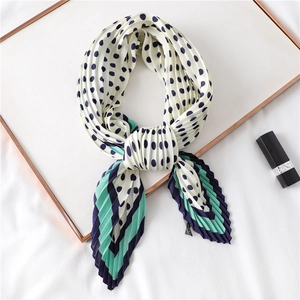 Foulard plissé à pois avec bords rayés présenté sur un panneau décoratif blanc